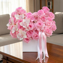 Load image into Gallery viewer, blossomstreetflorist heart-shaped arrangement with pink roses, white orchids, pearls, and ribbons in a white ceramic box.